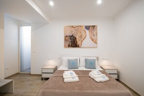 A hotel room with a bed, two bedside tables, a wall-mounted artwork, and a window with blinds.