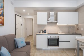 A modern kitchen with white cabinets, a built-in oven, and a coffee maker.