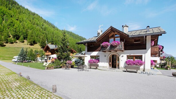 Een chalet met een balkon, houten gevel en een berg op de achtergrond.
