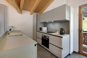 A modern kitchen with a sink, microwave, oven, and a coffee maker.