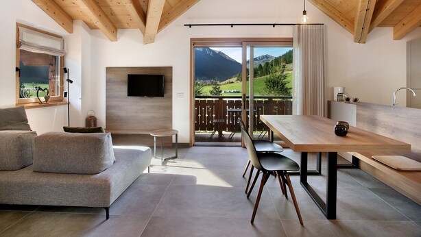 Un intérieur moderne avec un plafond en bois, un canapé, une table à manger et une vue sur un paysage montagneux.