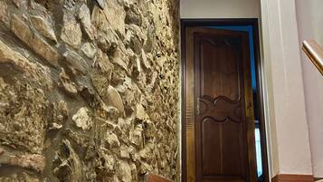 Un escalier avec un mur en pierre d’un côté et une porte en bois en haut.