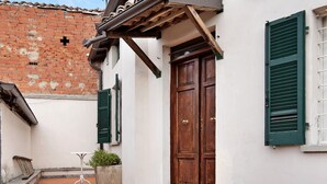 Un bâtiment avec une porte en bois, des volets verts et un mur blanc.