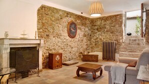 Une pièce aux murs de pierre, avec une cheminée, un canapé, une table en bois et un radiateur.