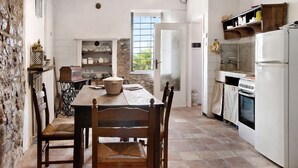 Une cuisine équipée d’une table à manger, de chaises, d’un réfrigérateur et d’une fenêtre.