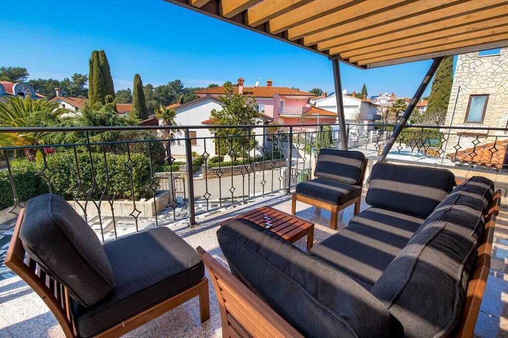 Un balcón con mobiliario de madera y vistas al vecindario.