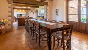 Un comedor con una larga mesa de madera, varias sillas y una chimenea de ladrillo al fondo.