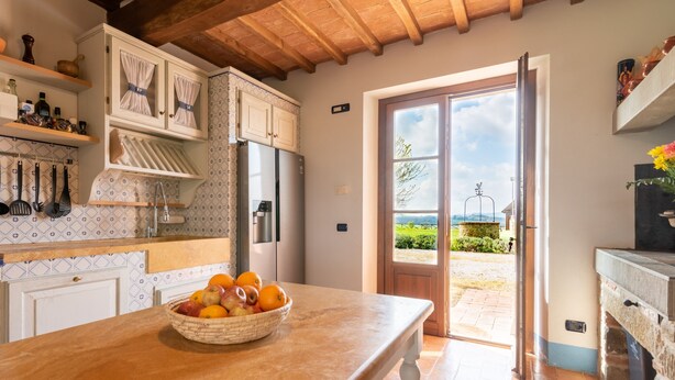 Una cocina con techo de madera, un ventanal grande y una puerta que da al exterior.
