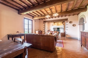 Un ambiente rustico con un tavolo da pranzo in legno, un divano in pelle e un camino.