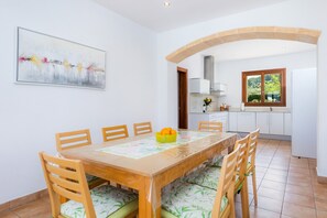 Ein Essbereich mit einem Holztisch, Stühlen, einer Obstschale und einem Bild an der Wand.