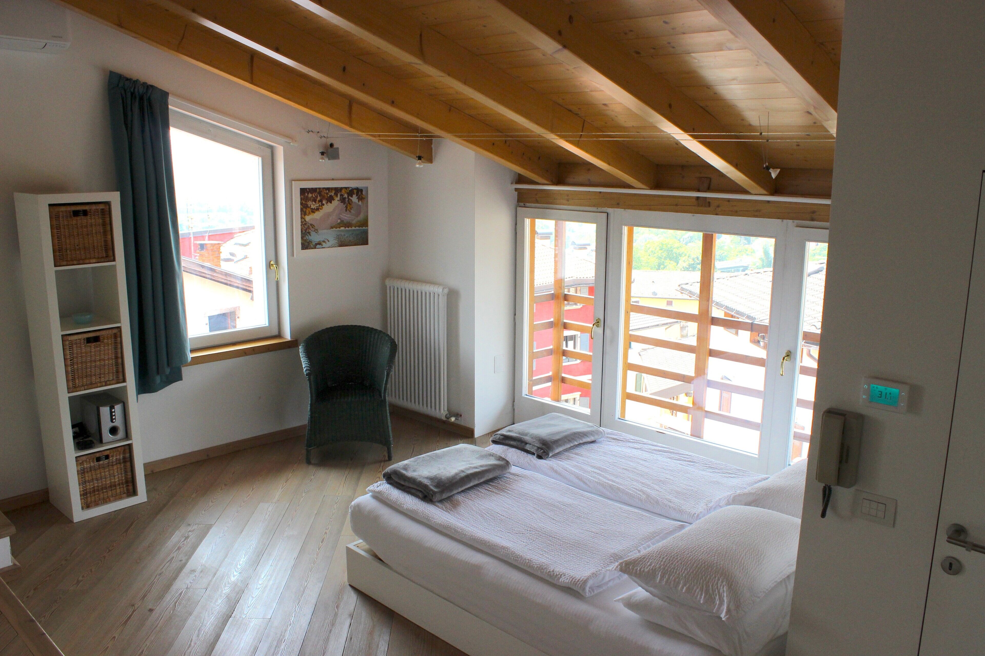 Une chambre à coucher avec un lit, une chaise, une fenêtre et une étagère avec des paniers.
