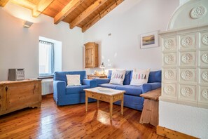 A cozy living room with a blue sofa, wooden coffee table, and a cabinet. - Wunderhorn Holiday Home with Private Terrace and Wi-Fi (Civezzano)