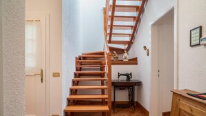A wooden staircase leading to a second floor, a sewing machine on a table, and a wooden cabinet. - Wunderhorn Holiday Home with Private Terrace and Wi-Fi (Civezzano)