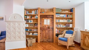 A room with a wooden bookshelf, a wicker chair, and a white cabinet. - Wunderhorn Holiday Home with Private Terrace and Wi-Fi (Civezzano)