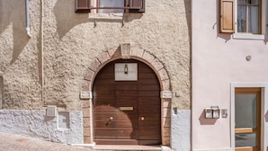 A building with a large wooden double door, a stone facade, and a small window above the door. - Wunderhorn Holiday Home with Private Terrace and Wi-Fi (Civezzano)