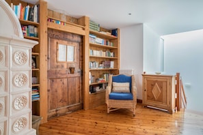 A room with wooden bookshelves, a wicker chair, and a cabinet. - Wunderhorn Holiday Home with Private Terrace and Wi-Fi (Civezzano)