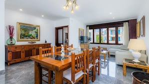 A spacious living area with a dining table, chairs, a sofa, and a TV. - Apartment 'Cala' with Mountain View, Wi-Fi and Air Conditioning (puerto pollensa)