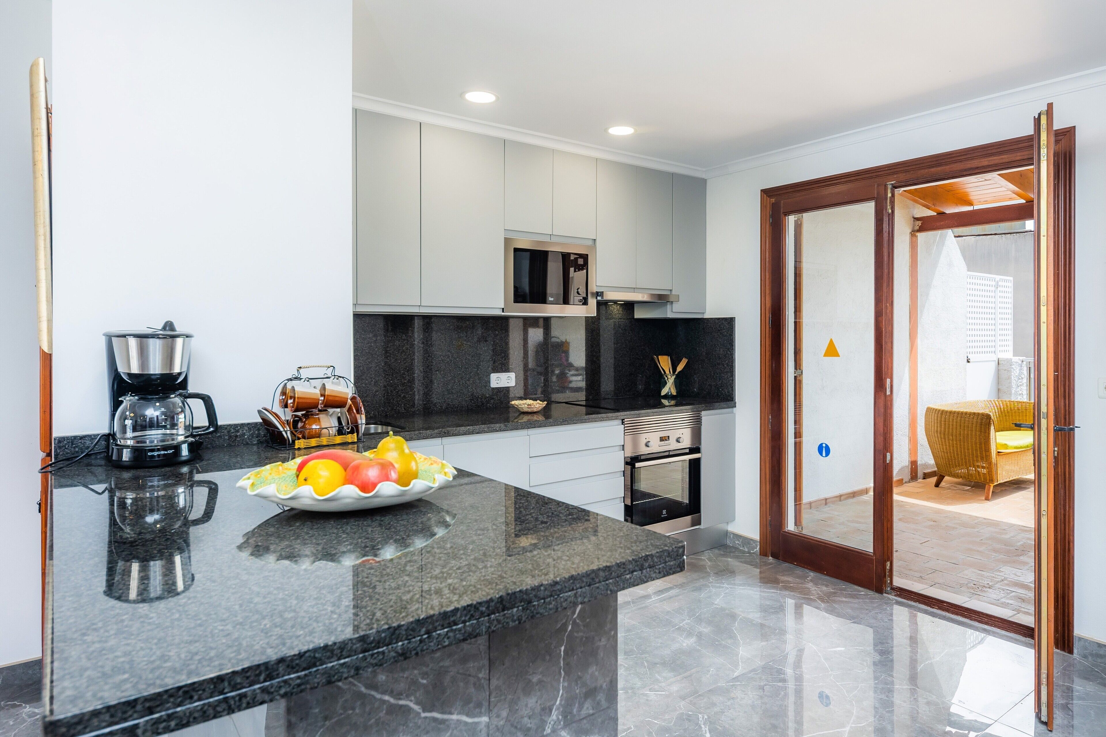 A modern kitchen with a granite countertop, stainless steel appliances, and a fruit bowl.
