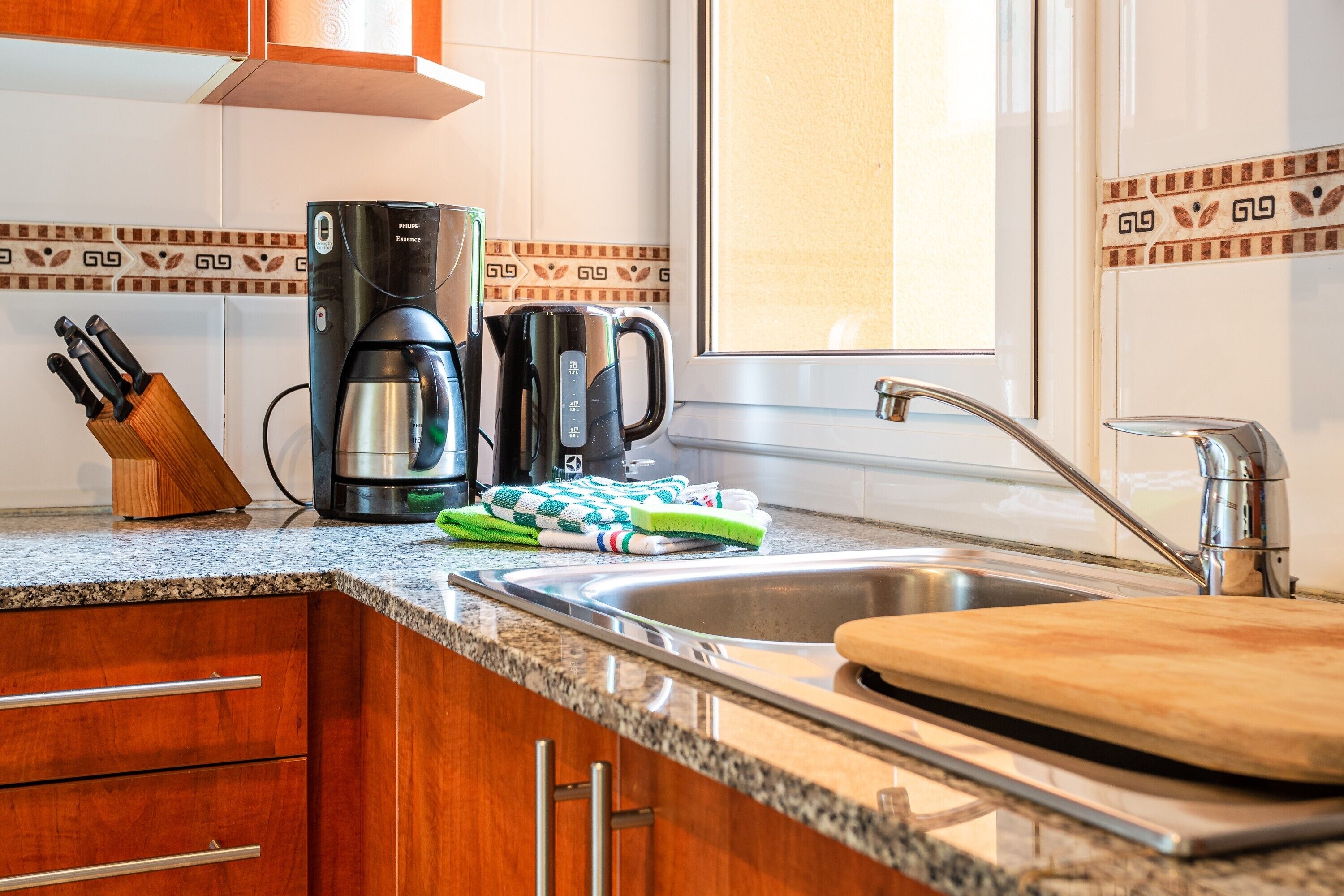 Una cocina con encimera de granito, electrodomésticos de acero inoxidable, armarios de madera y ventana con vistas.