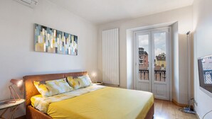 A bedroom with a bed, bedside table, lamp, artwork, window, and radiator. - Apartment "Crocetta 10" in City Centre with Wi-Fi (Milano)