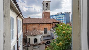 A view of a building with a bell tower, a courtyard, and a tree with yellow flowers. - Apartment "Crocetta 10" in City Centre with Wi-Fi (Milano)