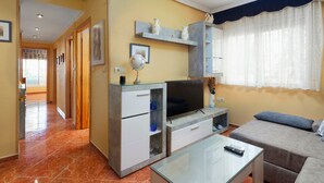 A living room with a TV, glass coffee table, sofa, and a hallway leading to another room. - Apartment 'Torre Del Mar' with Shared Pool, Shared Garden and Air Conditioning (Torre del Mar)