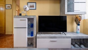 A modern living room with a flat-screen TV, built-in shelves with decorative items, and a marble-tiled floor. - Apartment 'Torre Del Mar' with Shared Pool, Shared Garden and Air Conditioning (Torre del Mar)