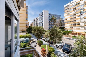 Un immeuble d’habitation doté de balcons, donnant sur la rue, avec des voitures garées.