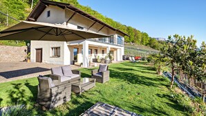 A modern house with a balcony, outdoor furniture, and a well-maintained lawn. - Holiday Apartment 'Weitblick Kaltern' with Mountain View, Private Terrace, and Garden (Caldaro sulla strada del vino)