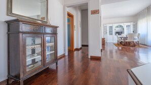 Une pièce spacieuse avec un buffet en bois, un coin repas comprenant des chaises et une table, et un grand miroir accroché au mur.