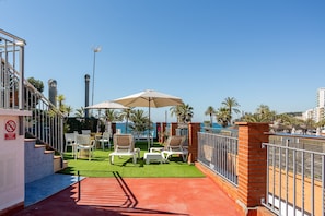 A rooftop terrace with outdoor seating, a pool, and a view of the city skyline.