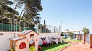 Un área de juegos infantiles con una casita, un tobogán y un patinete.