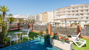 Una terraza en la azotea con mobiliario exterior, una piscina y vistas de edificios circundantes.