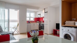 A modern kitchen with a dining area, a washing machine, and a red chair.
