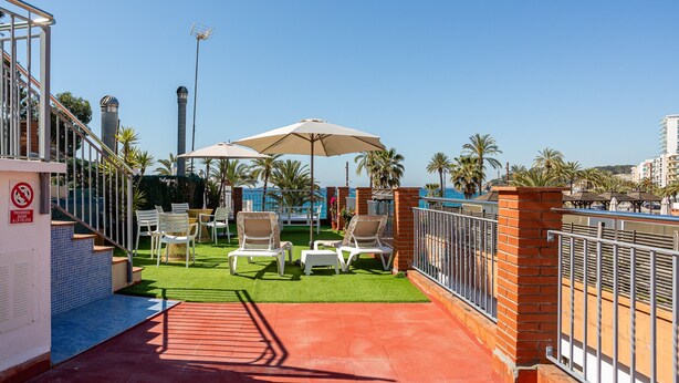 A rooftop terrace with outdoor seating, a pool, and a clear view of the city skyline.