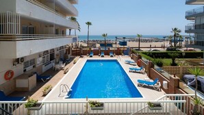 Un espace piscine comprenant des chaises longues, une piscine et une vue sur la plage.