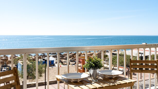 A wooden table with two bowls and a glass, a potted plant, and a view of the sea. - Studio apartment 'Ventana al Mar' with sea-facing terrace and air conditioning (Fuengirola)