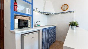 A compact kitchen with a microwave, sink, and a small refrigerator. - Studio apartment 'Ventana al Mar' with sea-facing terrace and air conditioning (Fuengirola)