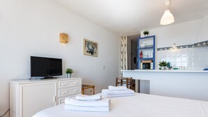 A hotel room with a bed, a television, a desk with a computer, a chair, and a small plant. - Studio apartment 'Ventana al Mar' with sea-facing terrace and air conditioning (Fuengirola)