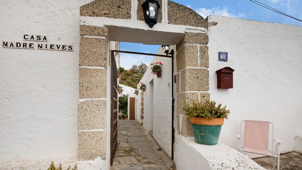 Un stretto sentiero in pietra conduce a un edificio bianco con un cartello che riporta 'CASA MADRE NIEVES'.