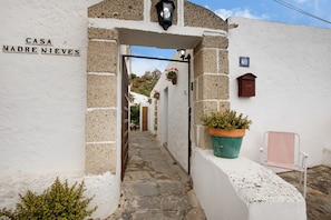 A narrow stone pathway leading to a white building with a sign reading 'CASA MADRE NIEVES.'