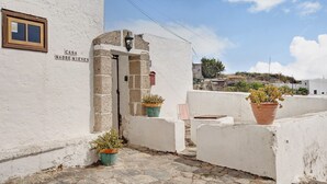 Un edificio bianco con un'insegna che recita 'CASA MADRENIEVES', un ingresso in pietra e piante in vaso sul tetto.