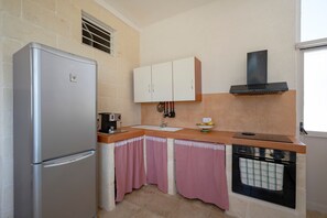 Une cuisine de taille réduite équipée d’un réfrigérateur, d’un évier, d’une cuisinière et d’une fenêtre.