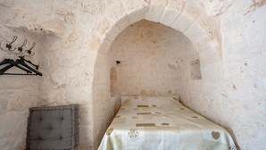 A room with a bed, a cushioned bench, and a stone archway. - Villa 'Stellina e Trullo Cecé' with Private Terrace, Wi-Fi and Air Conditioning (ostuni)