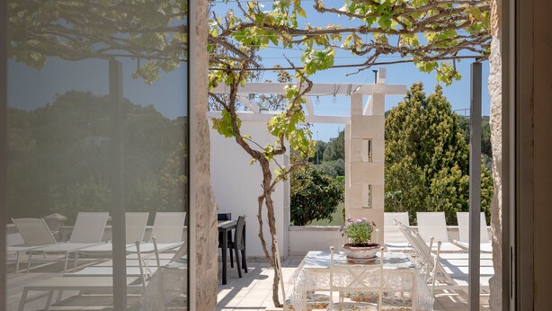 A patio with white chairs, a table, and a potted plant. - Villa 'Stellina e Trullo Cecé' with Private Terrace, Wi-Fi and Air Conditioning (ostuni)
