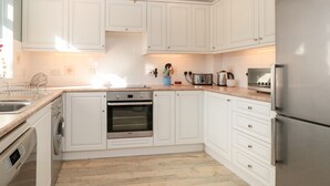 Una cocina moderna con armarios blancos, electrodomésticos de acero inoxidable y piso de madera.