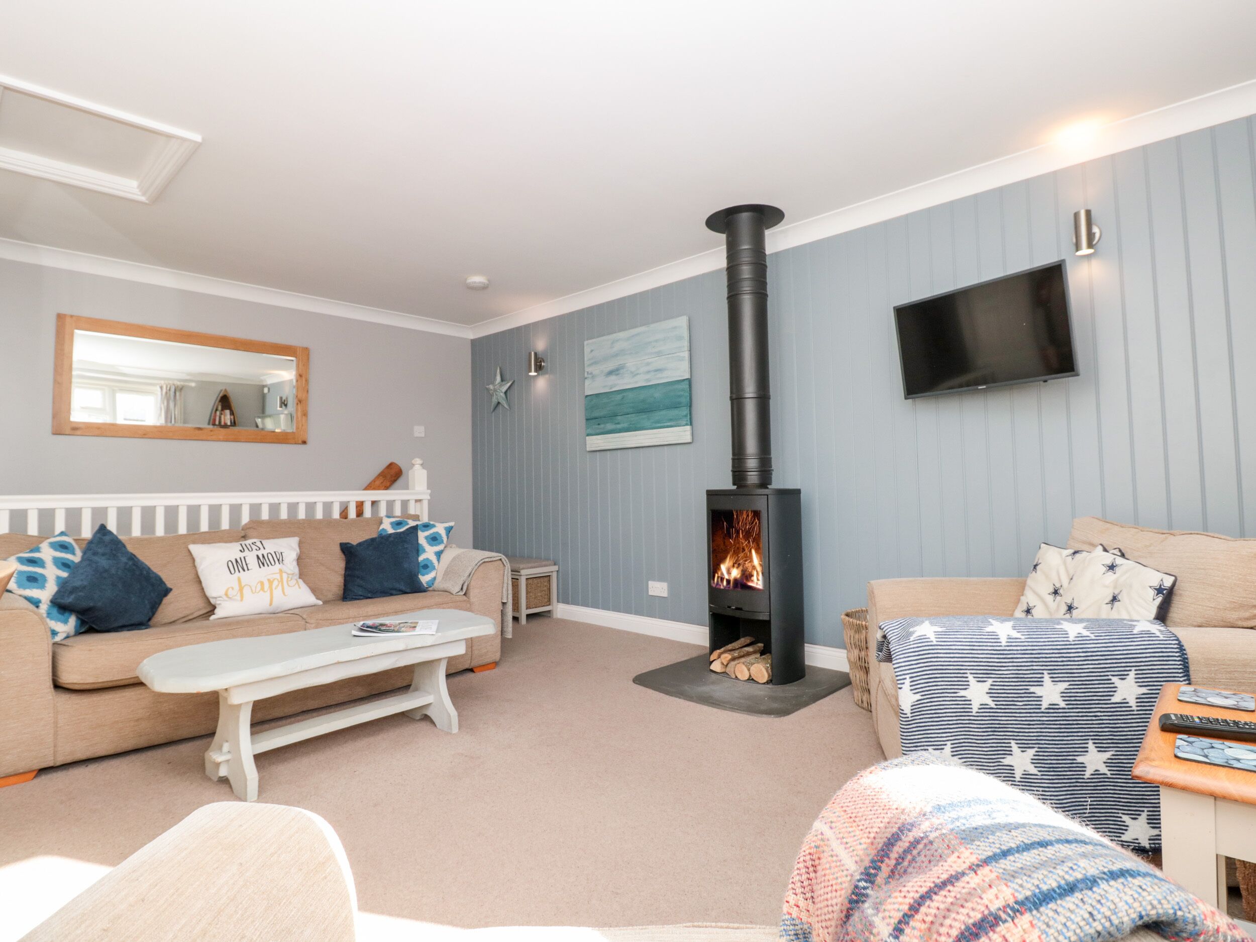A living room with a fireplace, a sofa, a coffee table, and a television mounted on the wall.