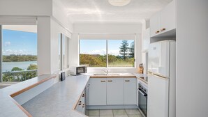 Een moderne keuken met witte kasten, een inbouwoven en uitzicht op een meer.