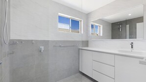 Een moderne badkamer met een inloopdouche, een grote spiegel en een raam.