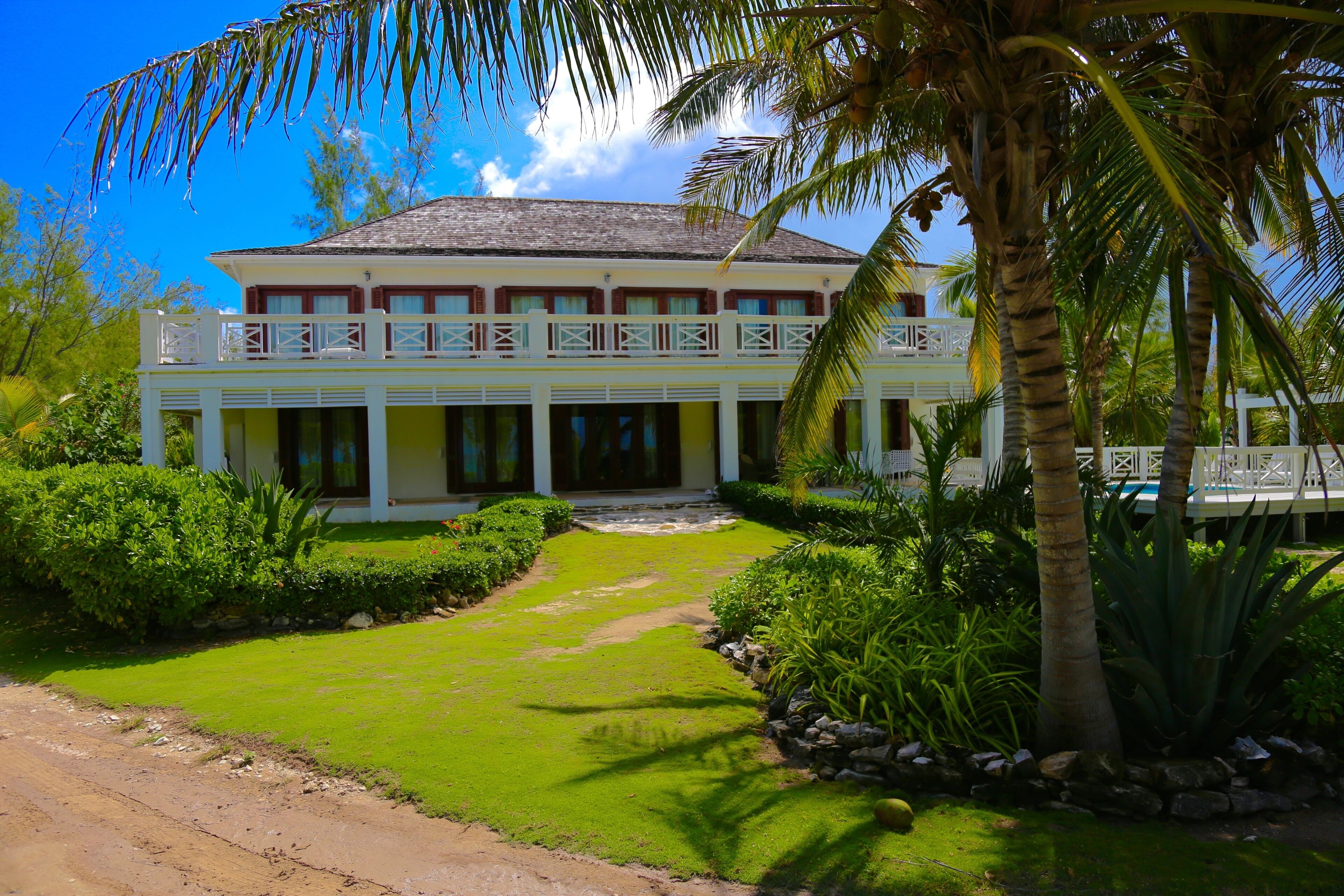 A two-story building with a balcony, surrounded by lush greenery and palm trees.